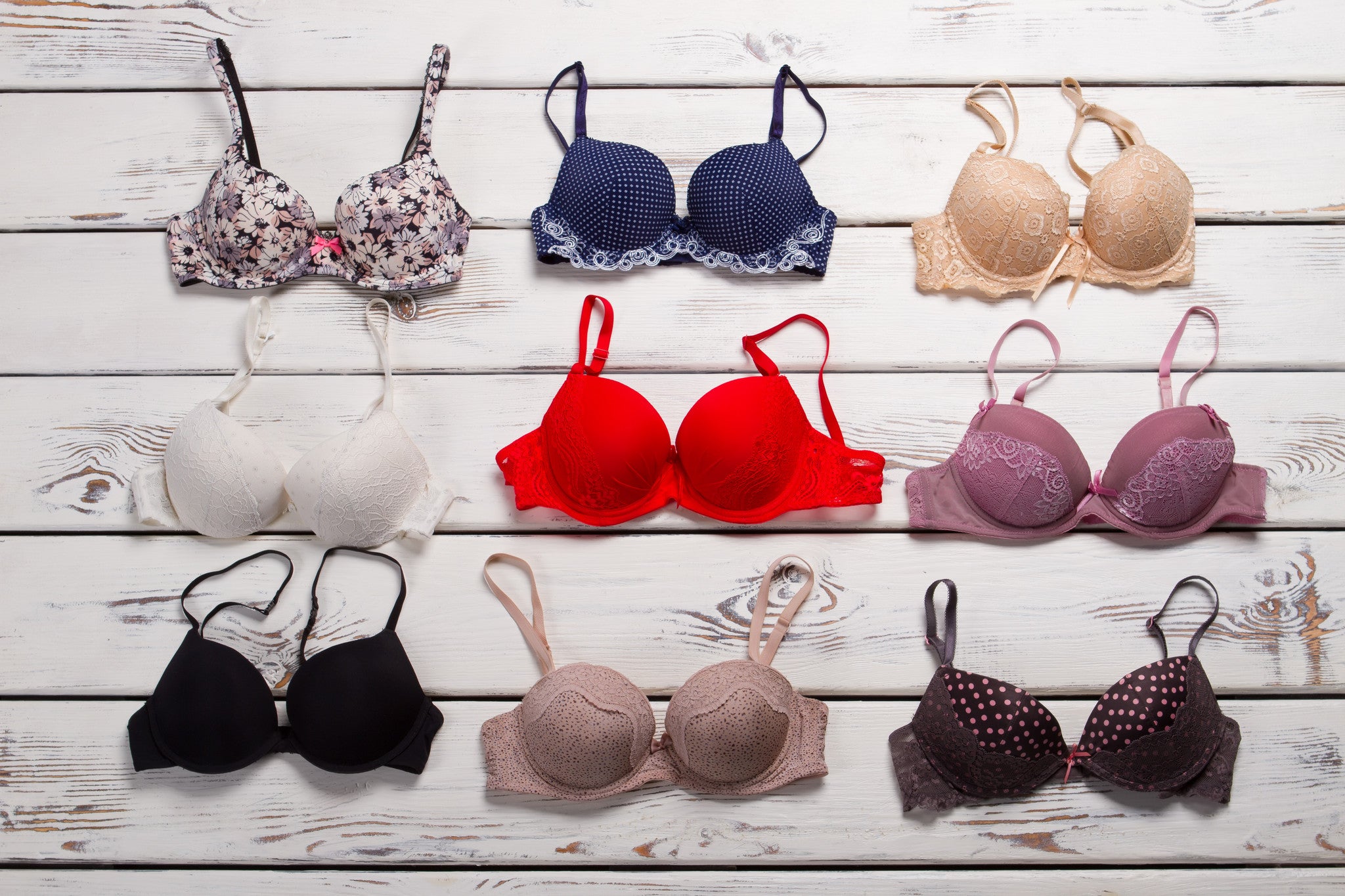 Different coloured bras on timber board