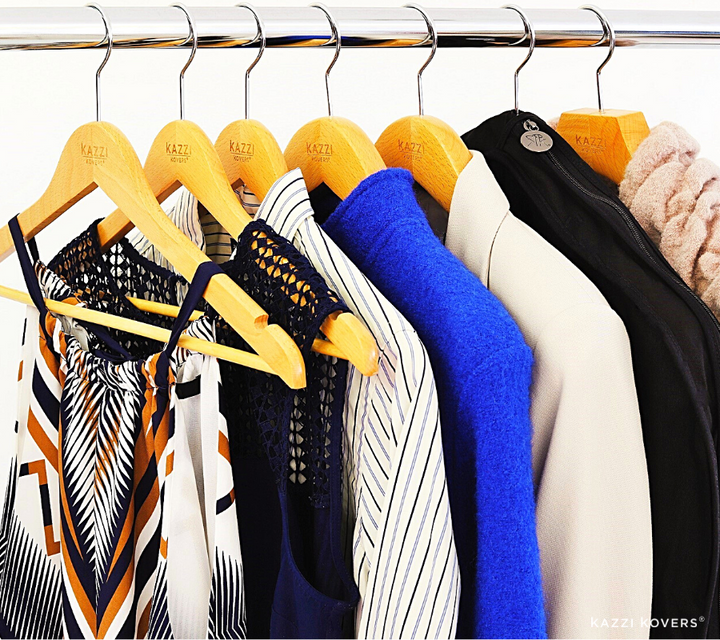 Different garments neatly organised side by side with black garment bag on a metal rack