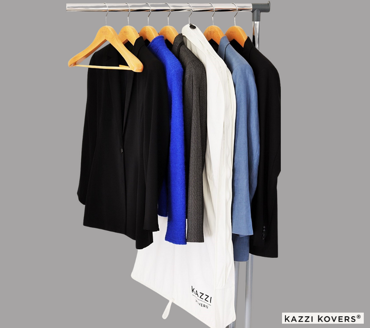 A mix of jackets and suits organised on rack with cream coloured garment bag