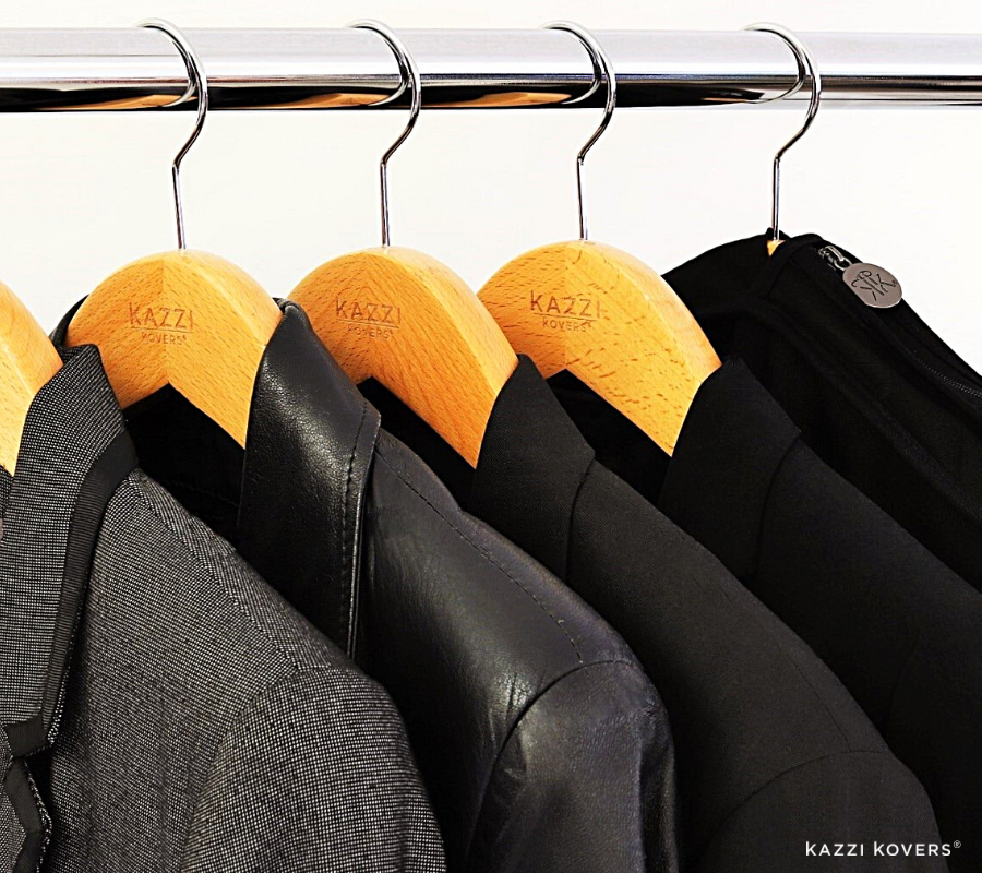 An assortment of garments with black garment bag hanging on rail