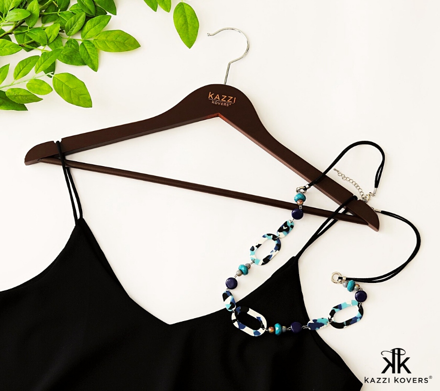 Black cami top laid flat on walnut clothes hanger