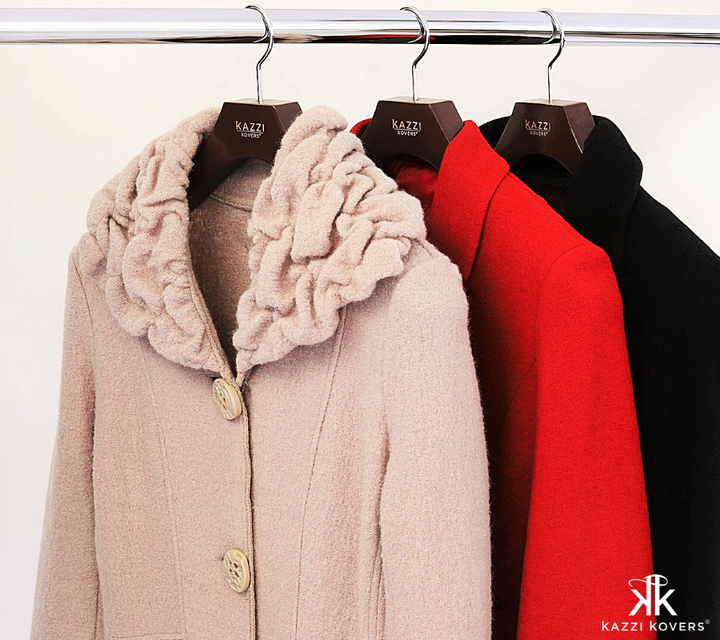 Beige, red and black wool coats displayed with walnut Kazzi Kovers coat hangers on rail